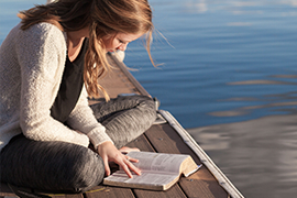 A person reading a book on a dock